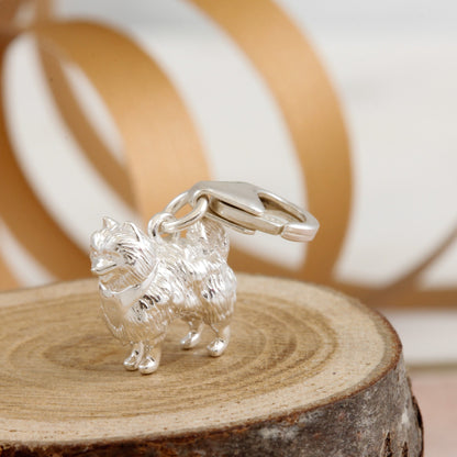 A silver Pomeranian dog charm shaped like a tiny puppy, detailed with realistic features, by Scarlett Jewellery.