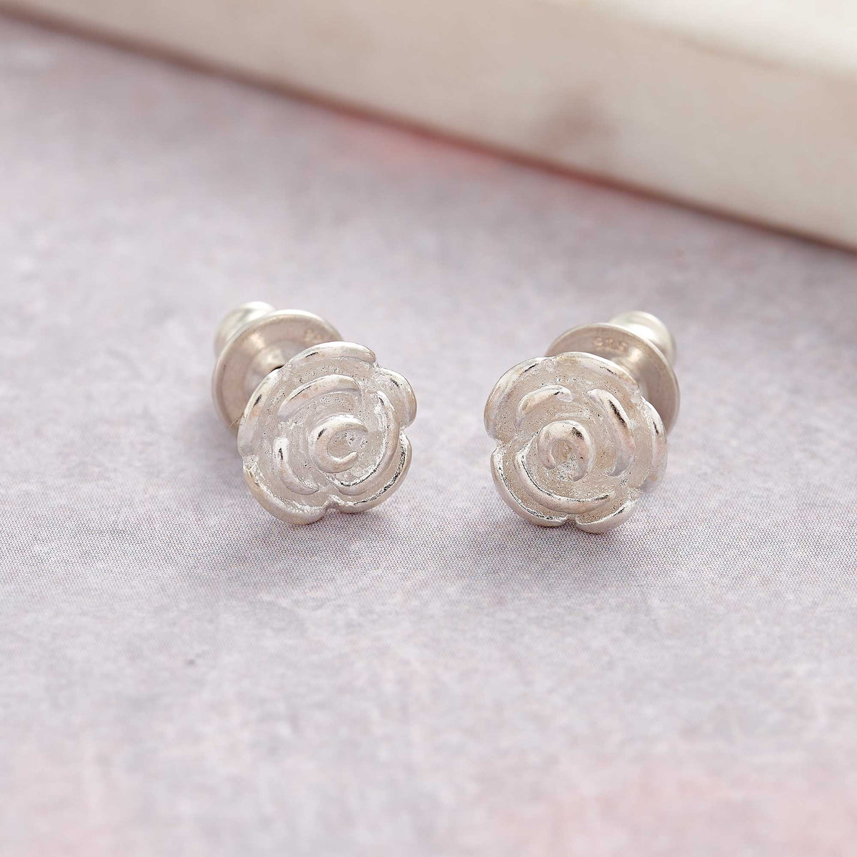 Silver stud earrings featuring a delicate rose flower design by Scarlett Jewellery.