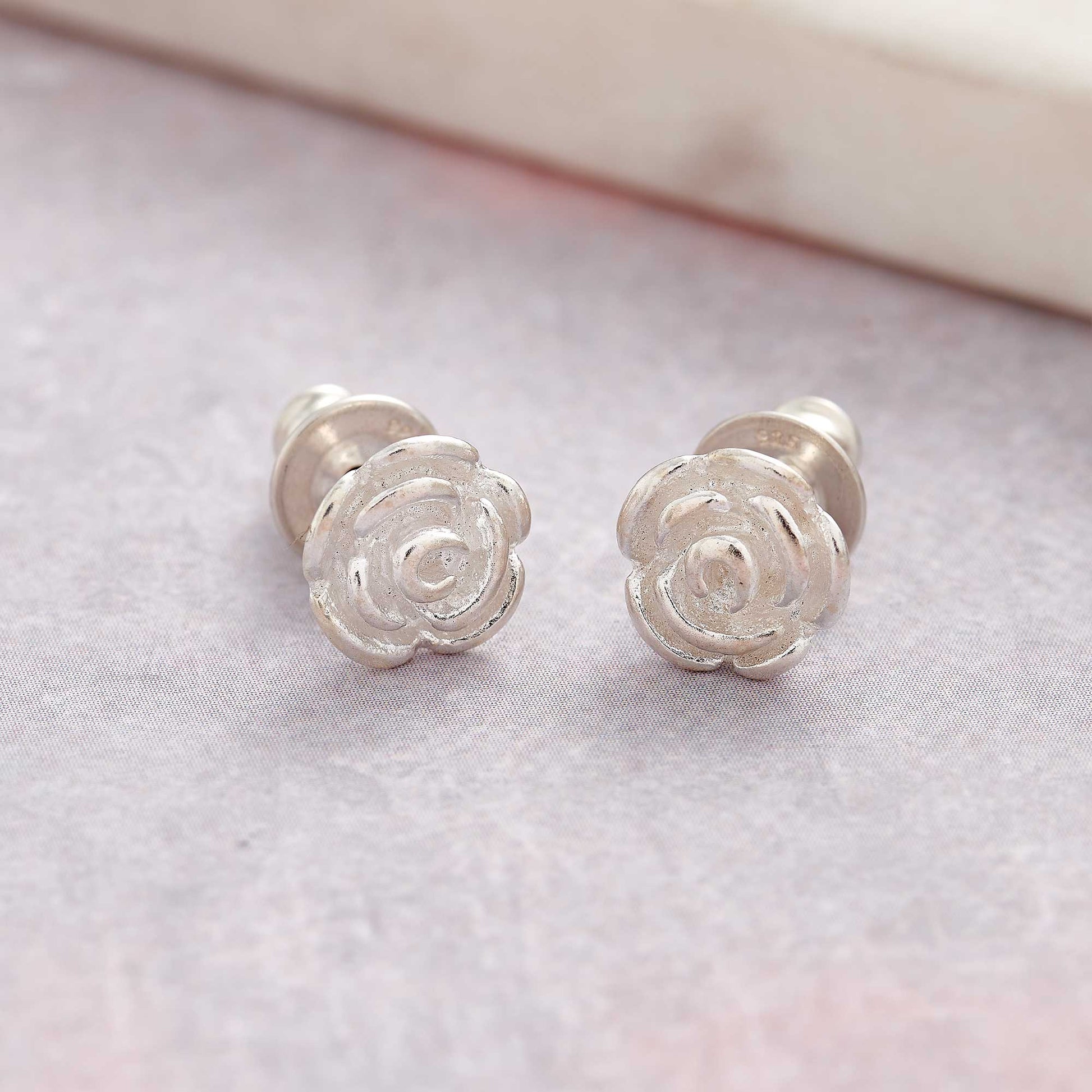 Silver stud earrings featuring a delicate rose flower design by Scarlett Jewellery.