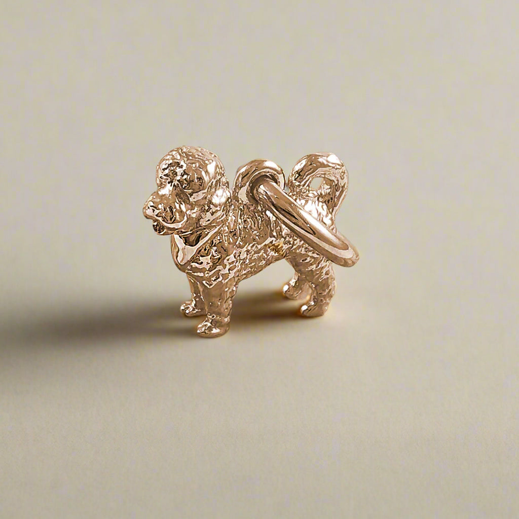A silver cavapoo dog charm hangs from a chain, detailed with realistic features and textured fur, by Scarlett Jewellery.