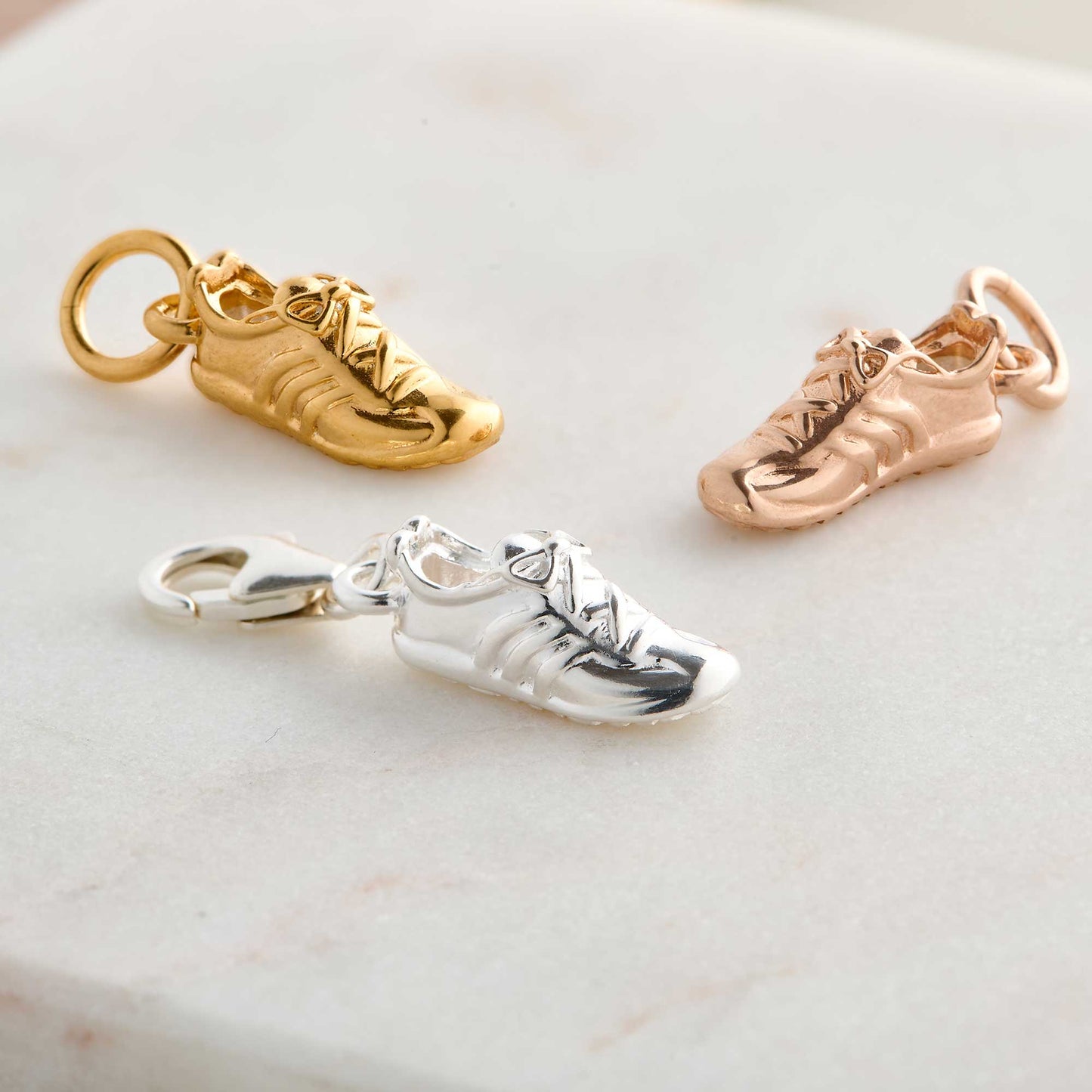 Silver charm with a running shoe design on a white background by Scarlett Jewellery.