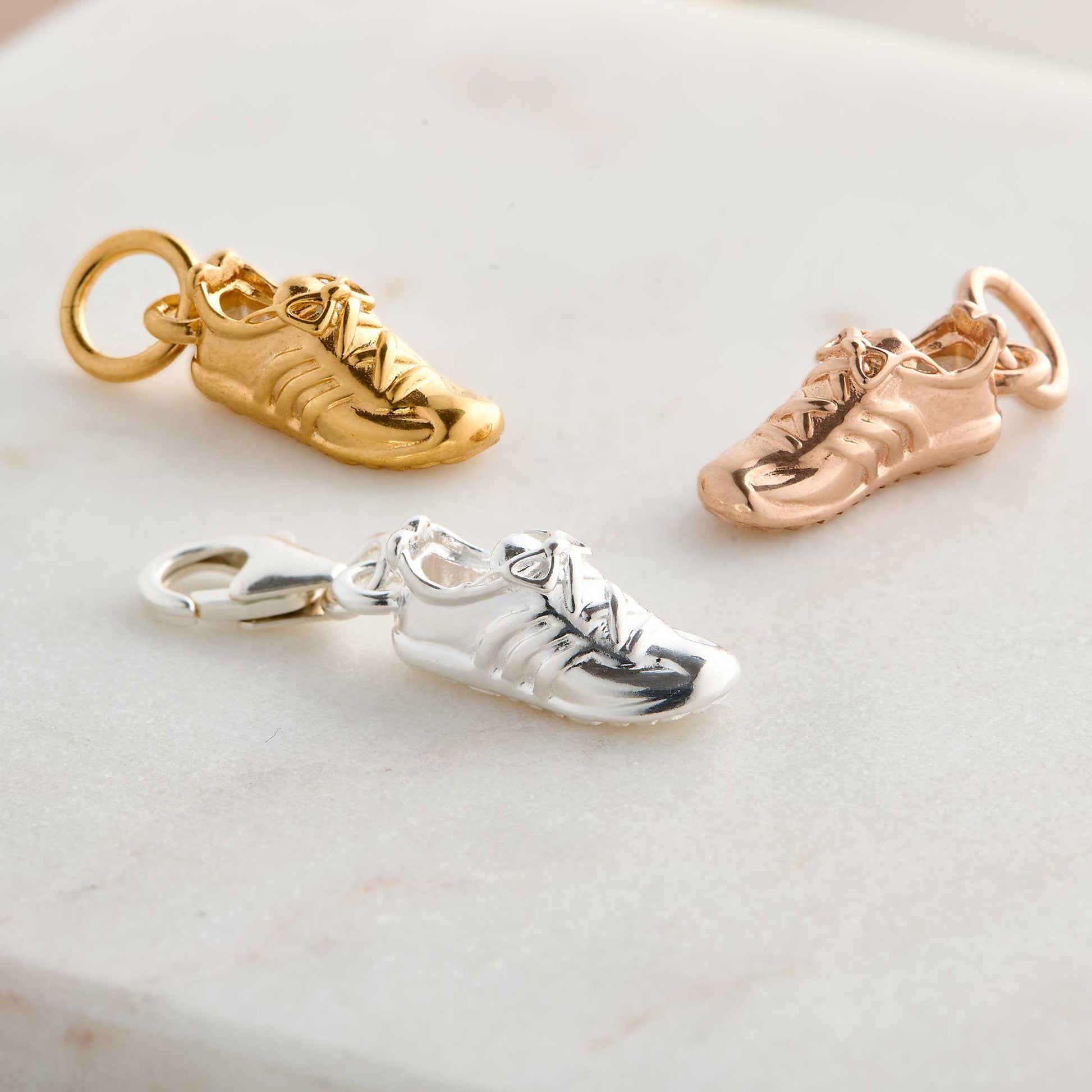 Silver charm with a running shoe design on a white background by Scarlett Jewellery.