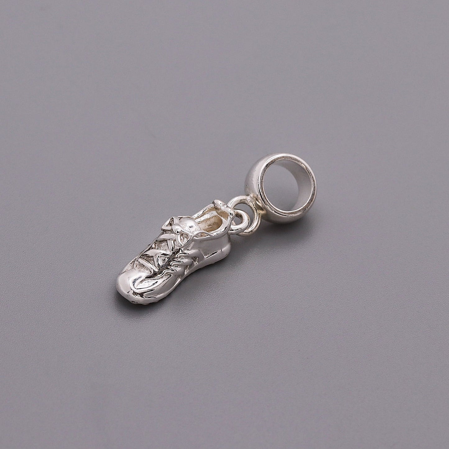 Detailed silver charm shaped like a running shoe, featuring laces and a shiny finish, from the Running Shoe Silver Charm by S