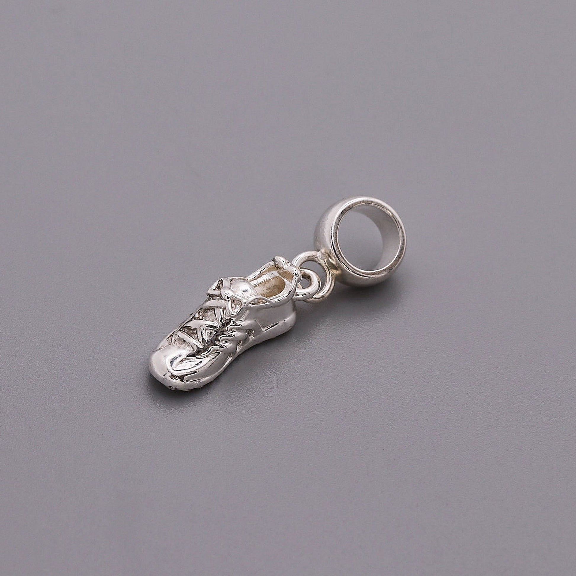 Detailed silver charm shaped like a running shoe, featuring laces and a shiny finish, from the Running Shoe Silver Charm by S