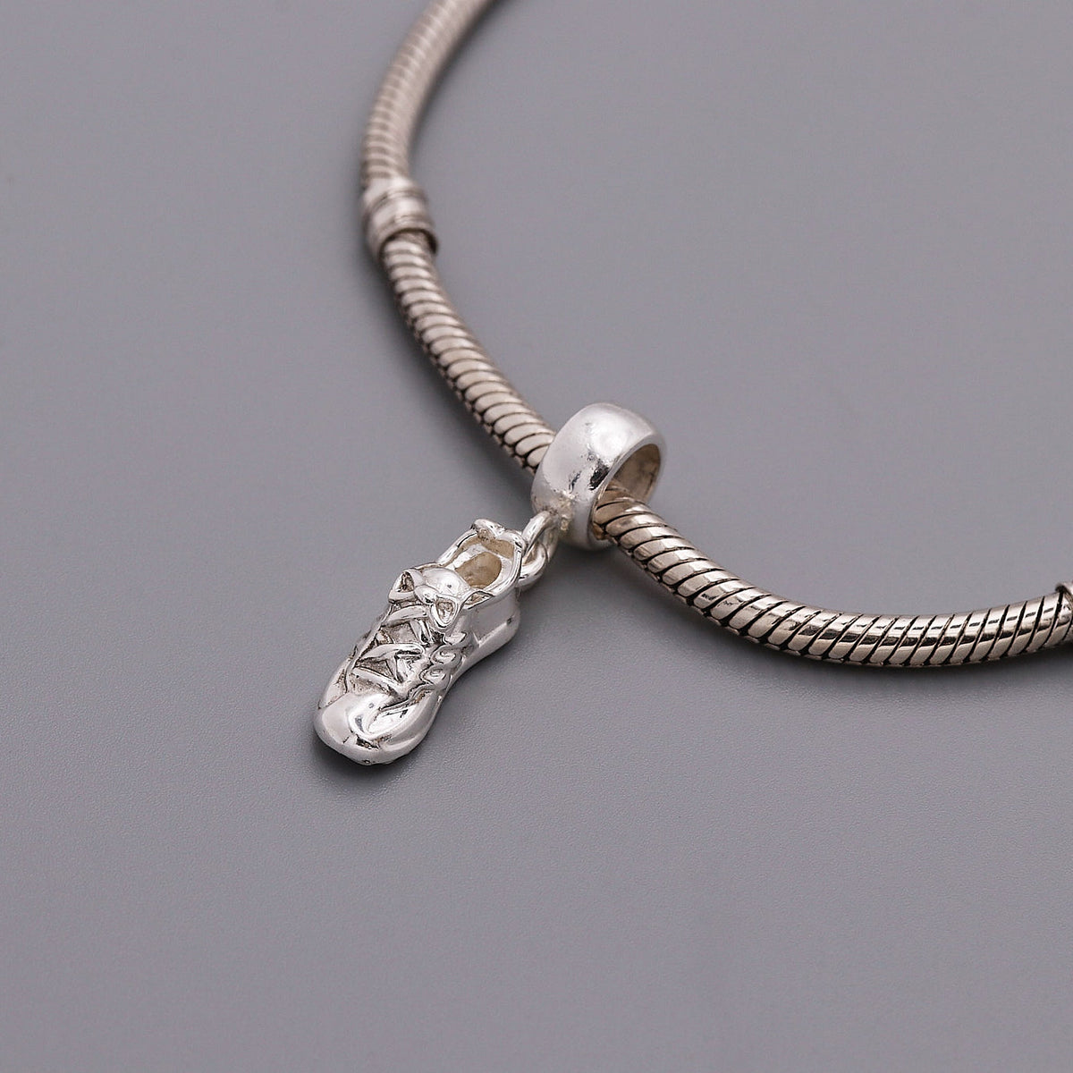 Silver charm with detailed etching on a running shoe by Scarlett Jewellery.