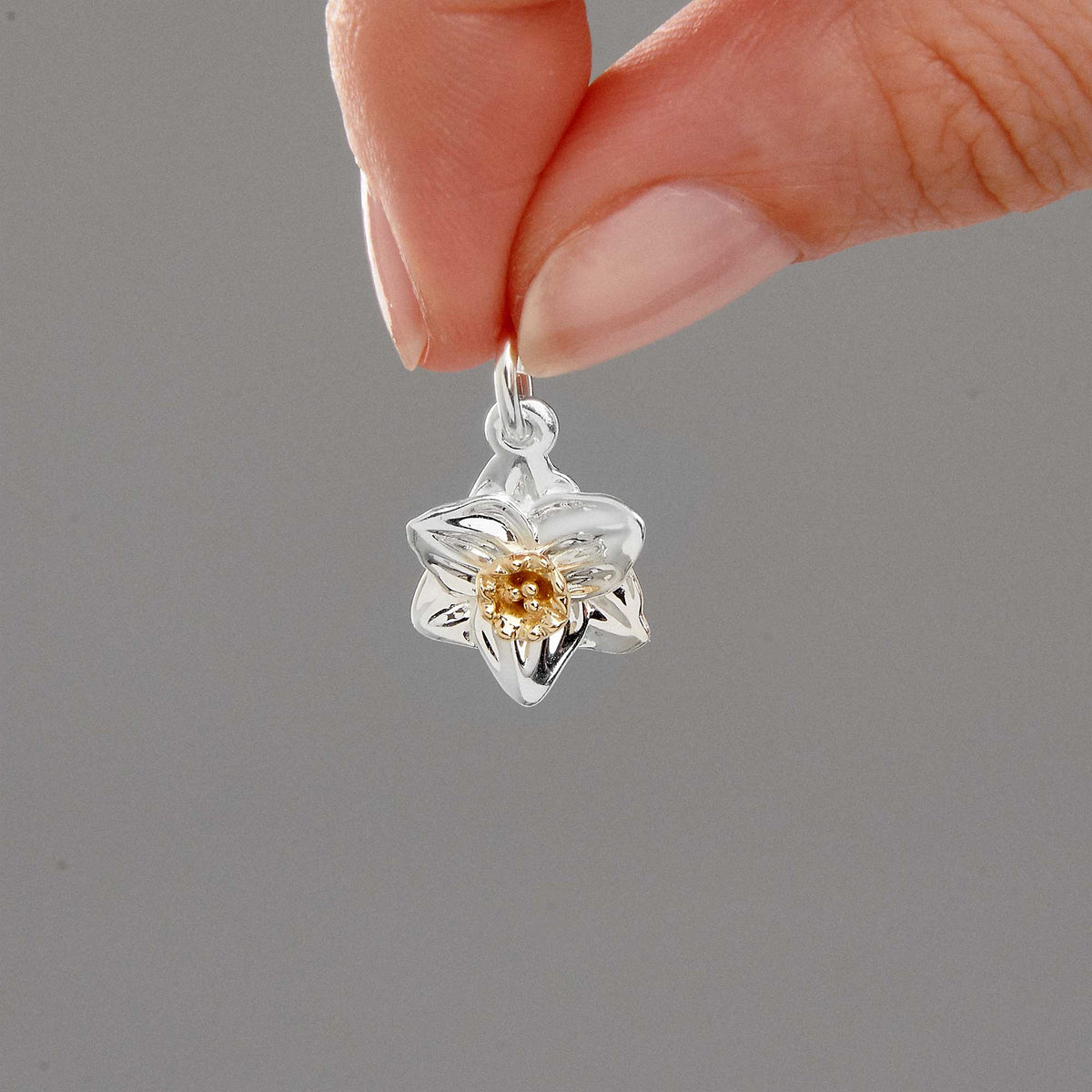 A daffodil flower charm in silver and solid gold, detailed with intricate petal textures, by Scarlett Jewellery.