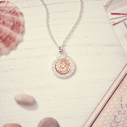 A silver and rose gold St Christopher necklace with personalized engraving, displayed on a soft background by Scarlett Jewell