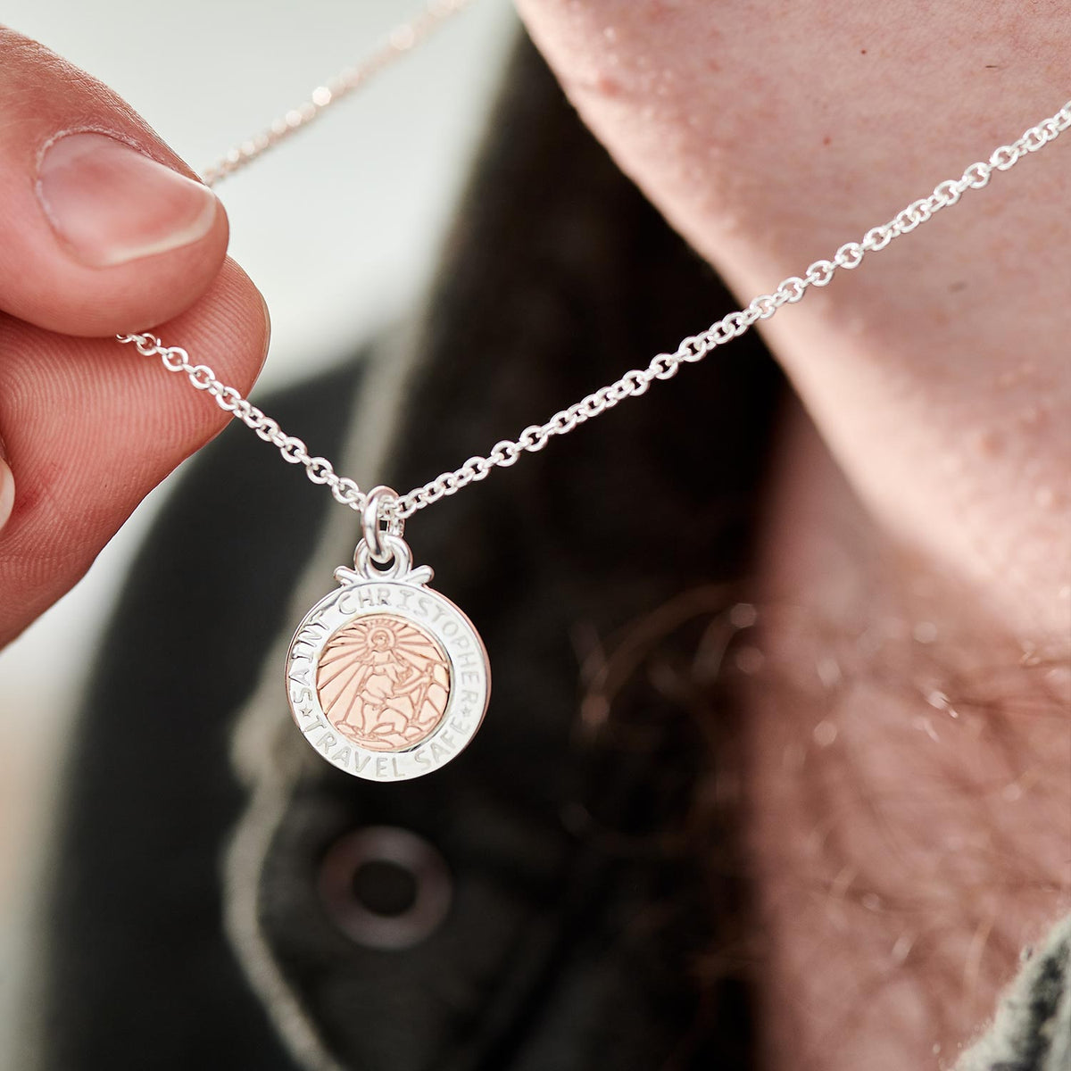 A silver and rose gold St Christopher necklace with personalized engraving, displayed on a soft white background by Scarlett 