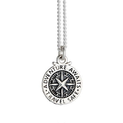 A silver compass charm with engraved details, displayed on a soft background, part of the Travel Safe collection by Scarlett 