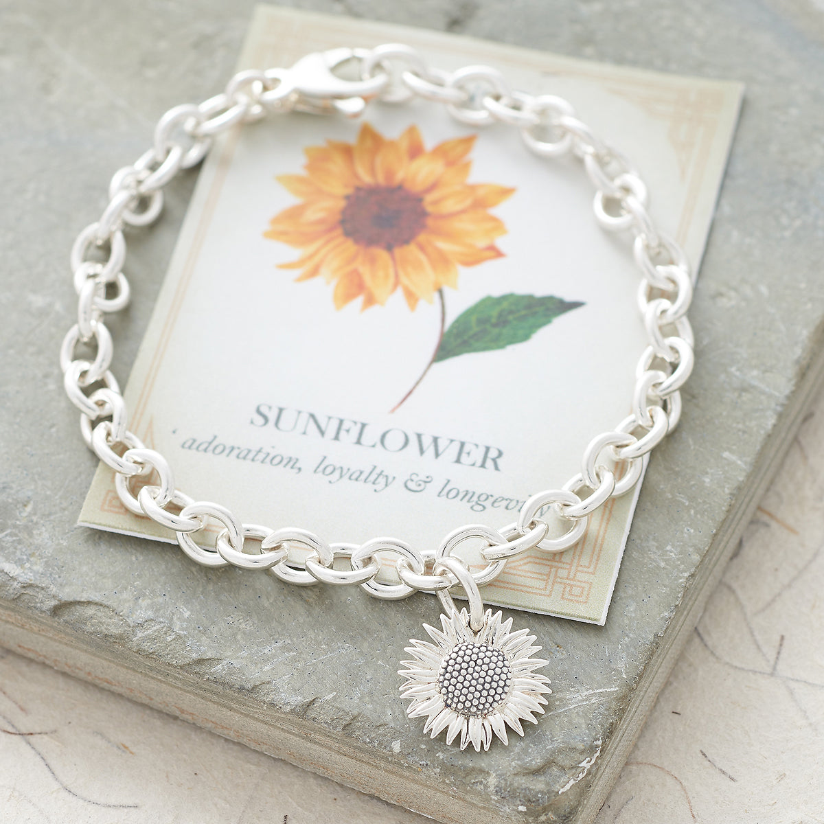 Sunflower silver charm with intricate detailing, displayed on a soft white background by Scarlett Jewellery.