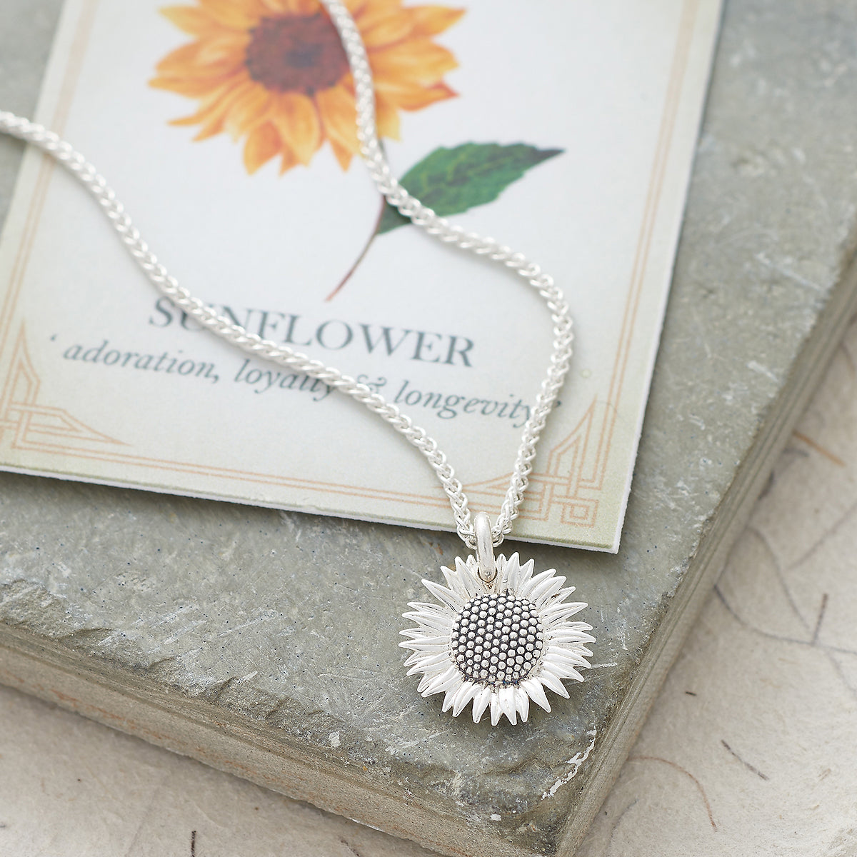 Sunflower silver charm with intricate details, displayed on a soft white background by Scarlett Jewellery.
