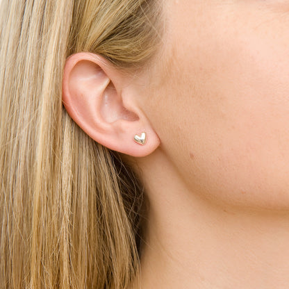 Sweetheart silver stud earrings with delicate heart design, close-up shot by Scarlett Jewellery.