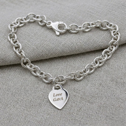 A silver heart tag charm bracelet with personalized engraving, featuring a delicate chain and small heart-shaped pendant by S