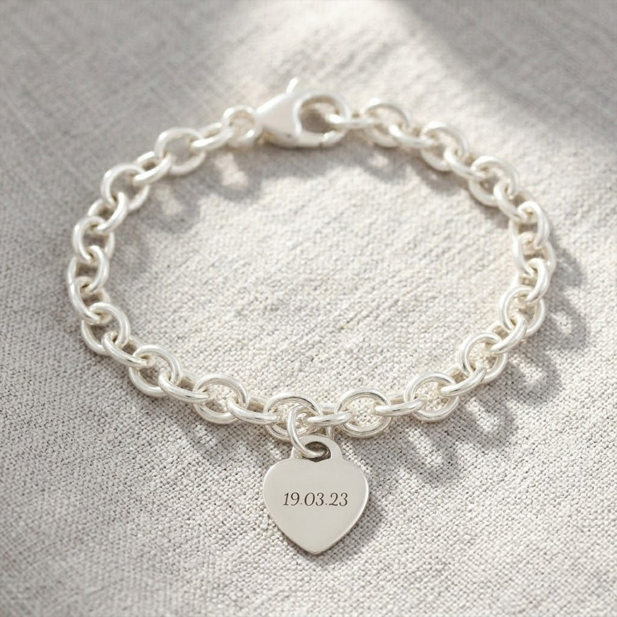 A silver heart tag charm bracelet with personalized engraving, featuring a delicate chain and tiny heart pendant by Scarlett 