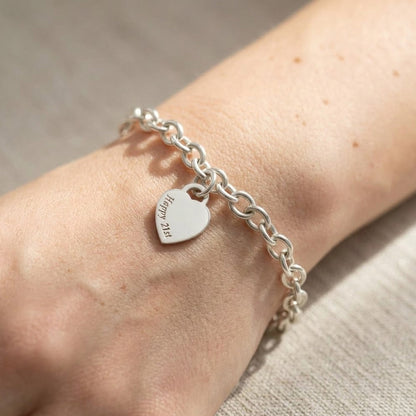 A silver heart tag charm bracelet with personalized engraving, featuring a delicate chain and tiny heart pendant by Scarlett 