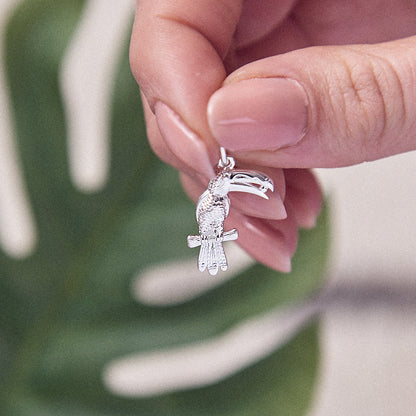 Silver toucan parrot charm with intricate detailing, displayed on a soft velvet background by Scarlett Jewellery.