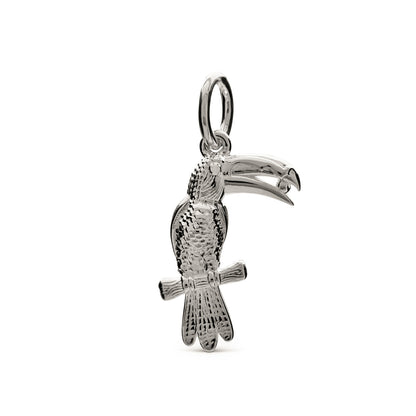 Silver toucan parrot charm with intricate detailing, displayed on a soft velvet background by Scarlett Jewellery.