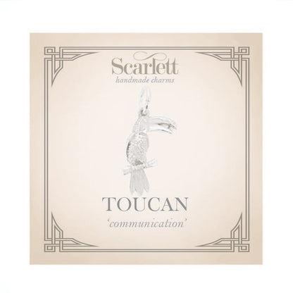 Silver toucan parrot charm with intricate detailing, displayed on a soft blue background, by Scarlett Jewellery.