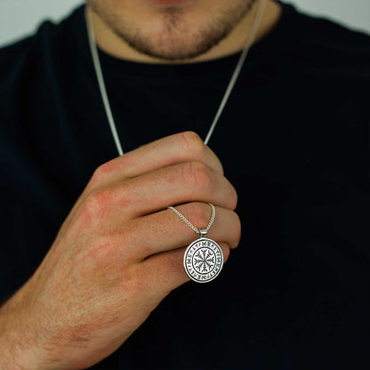 A silver Viking rune necklace with personalized engraving, displayed on a wooden surface, by Scarlett Jewellery.