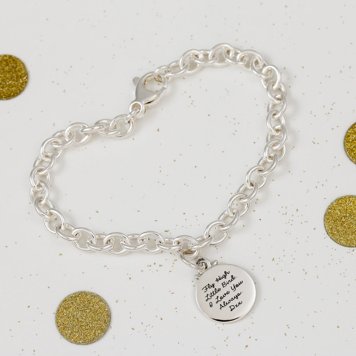 A silver compass charm with engraved details, displayed on a soft background, part of the Travel Safe collection by Scarlett 