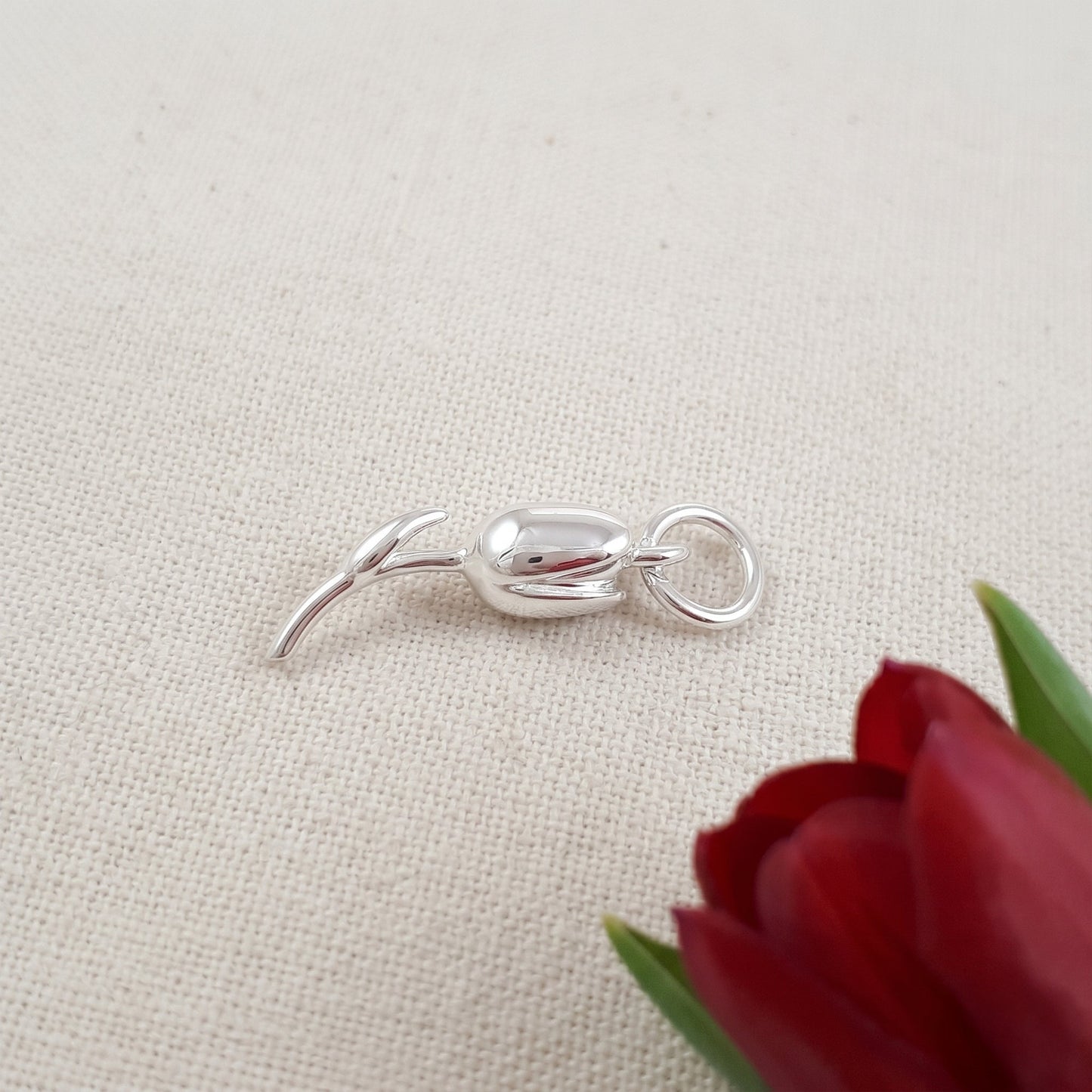 A silver tulip flower charm with intricate detailing, displayed on a soft white background, by Scarlett Jewellery.